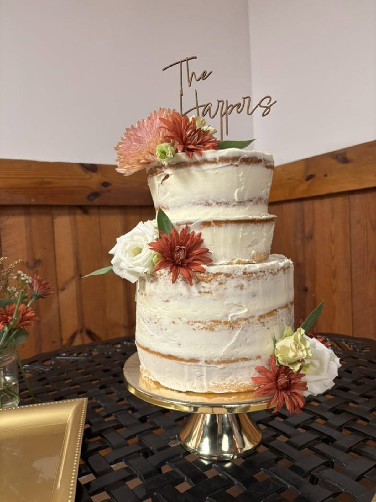 A tiered naked wedding cake with fresh flowers